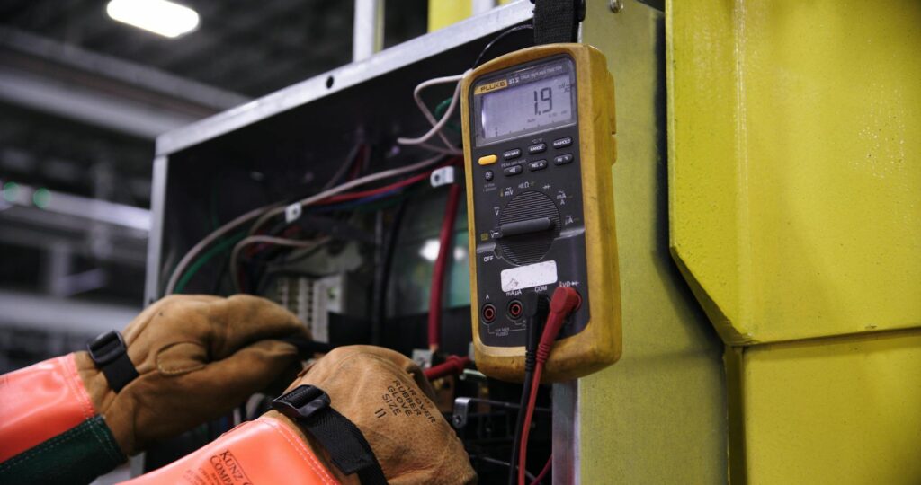 Engineer performing EICR electrical testing on industrial panel in Northampton